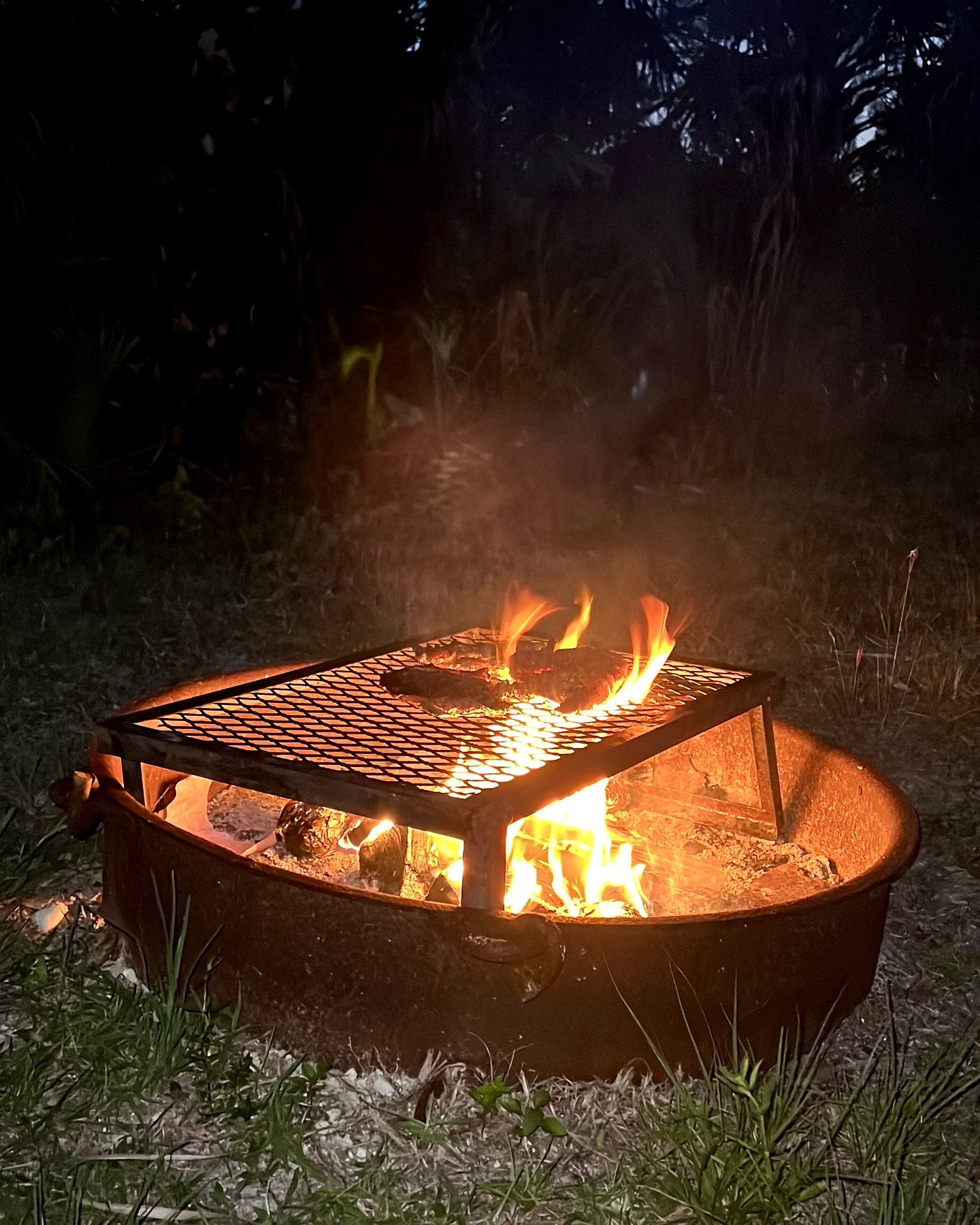 Contained campfire burning in a steel fire ring at night