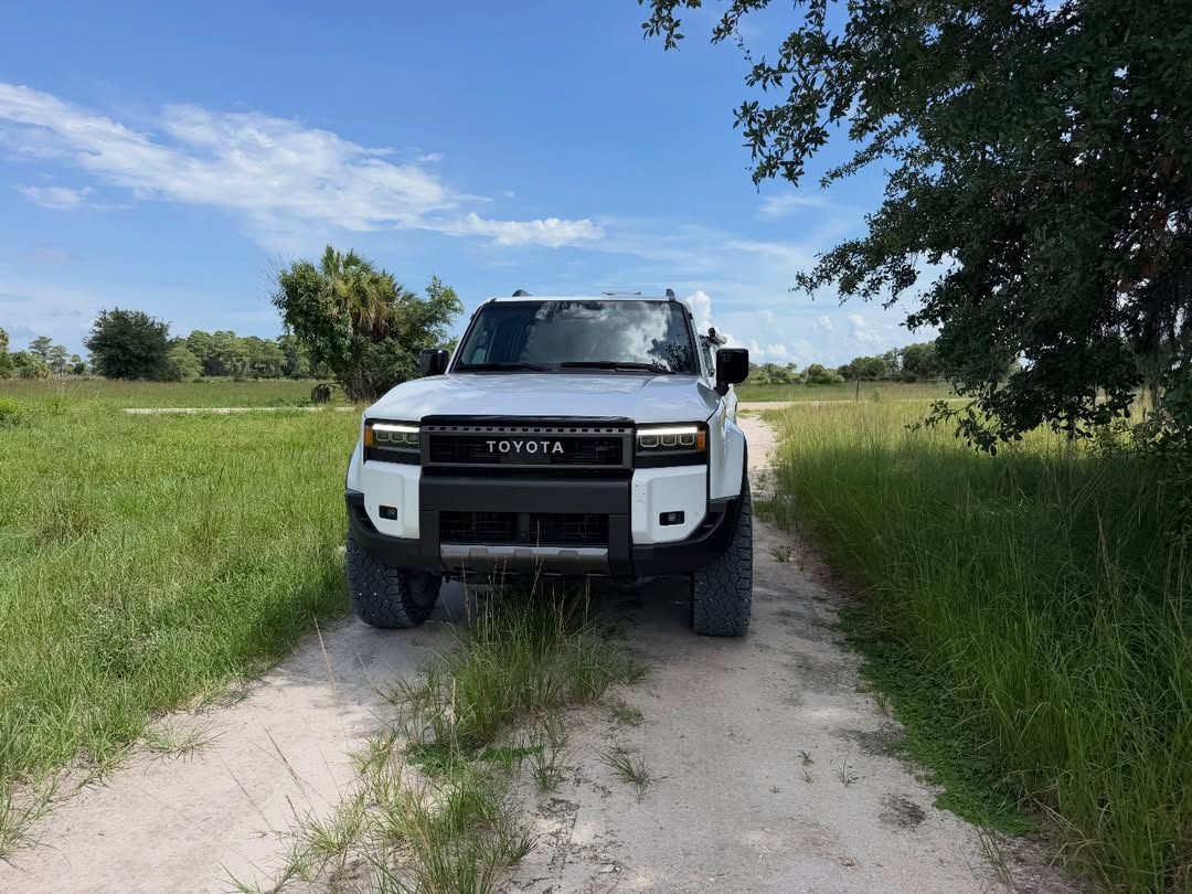 Overland truck on a sandy trail under summer clouds